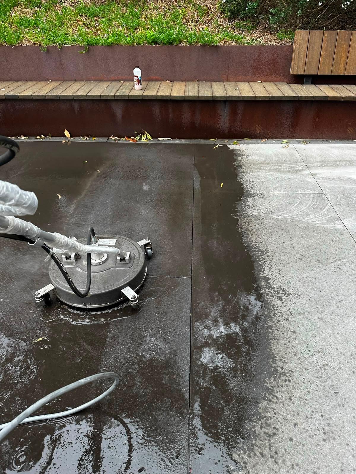 Technician pressure washing paved walkway outside a corporate campus building