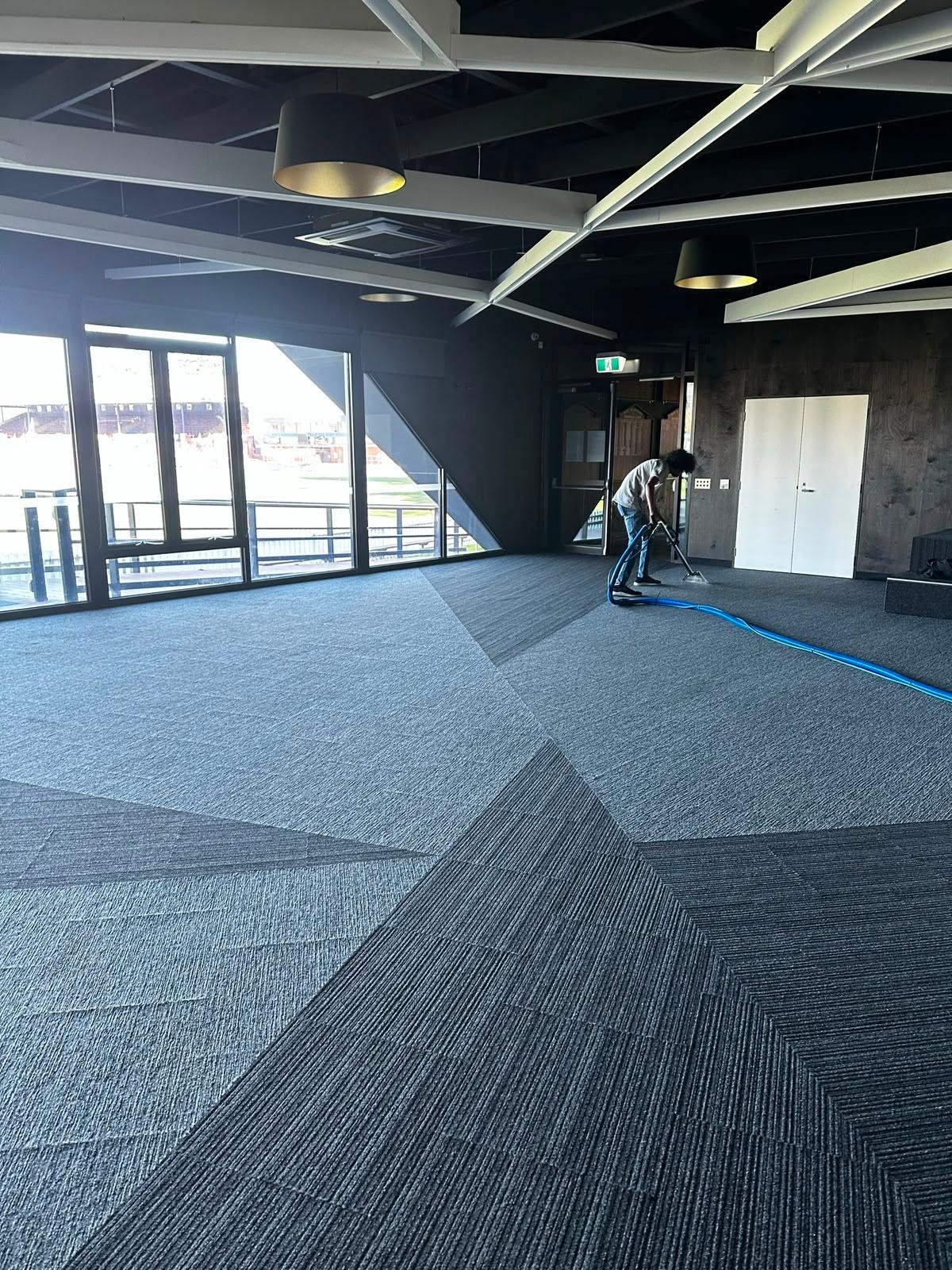 Carpet extraction cleaning in a waterfront function centre with stadium views through the windows