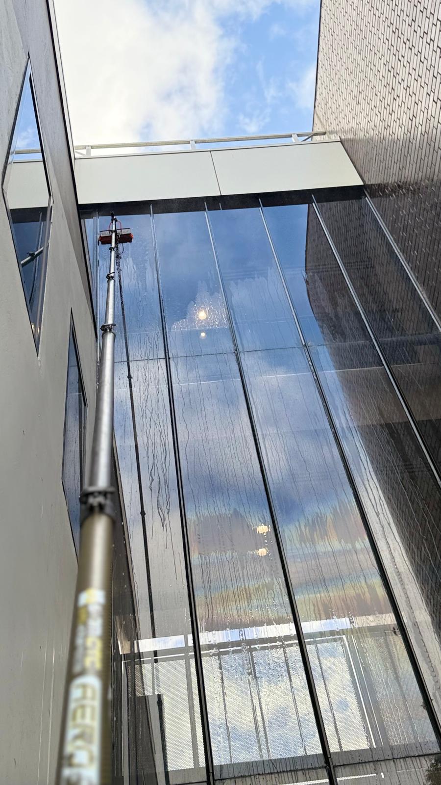 Water-fed pole window cleaning the glass atrium of a multi-storey building