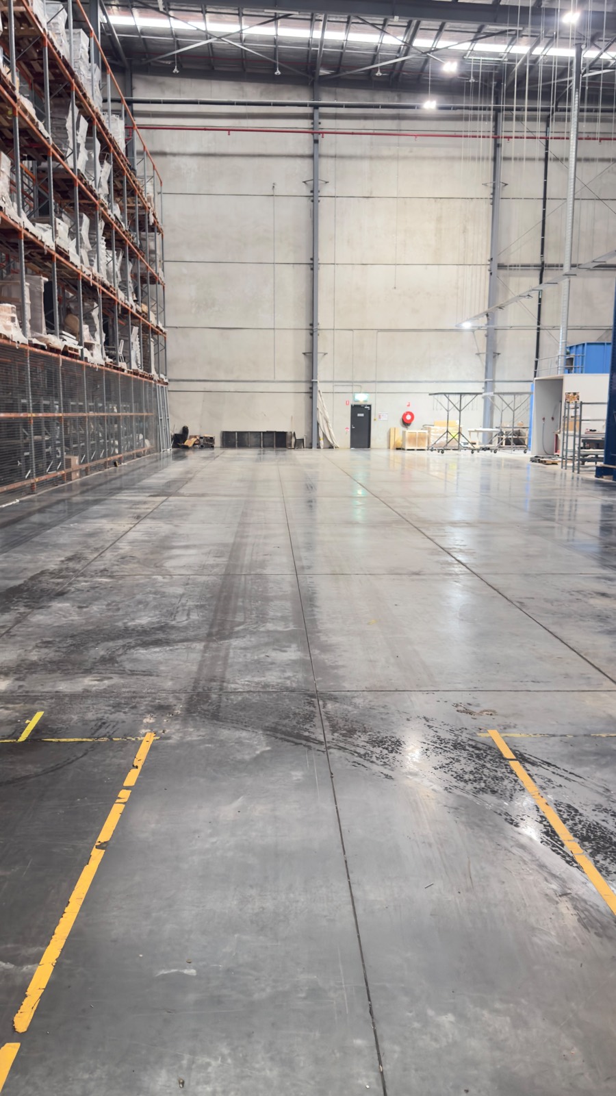 Distribution warehouse concrete floor, oil-stained and tyre-marked above, scrubbed back to clean concrete below